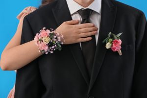 Young,Woman,With,Corsage,Hugging,Her,Prom,Date,On,Blue